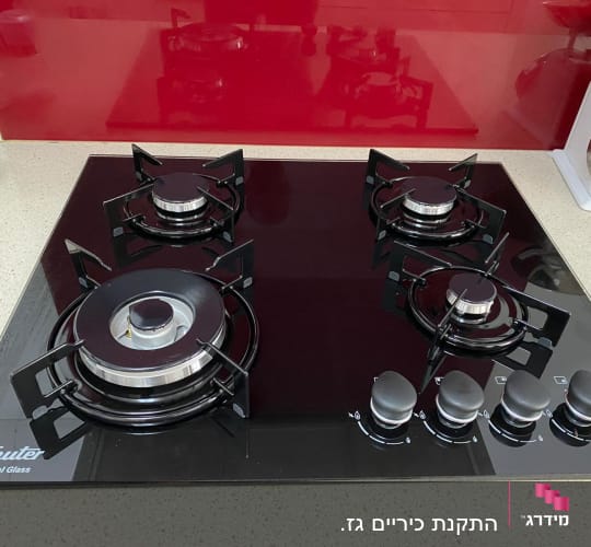 כיריים גז שחורות עם ארבעה מבערים וכפתורי שליטה